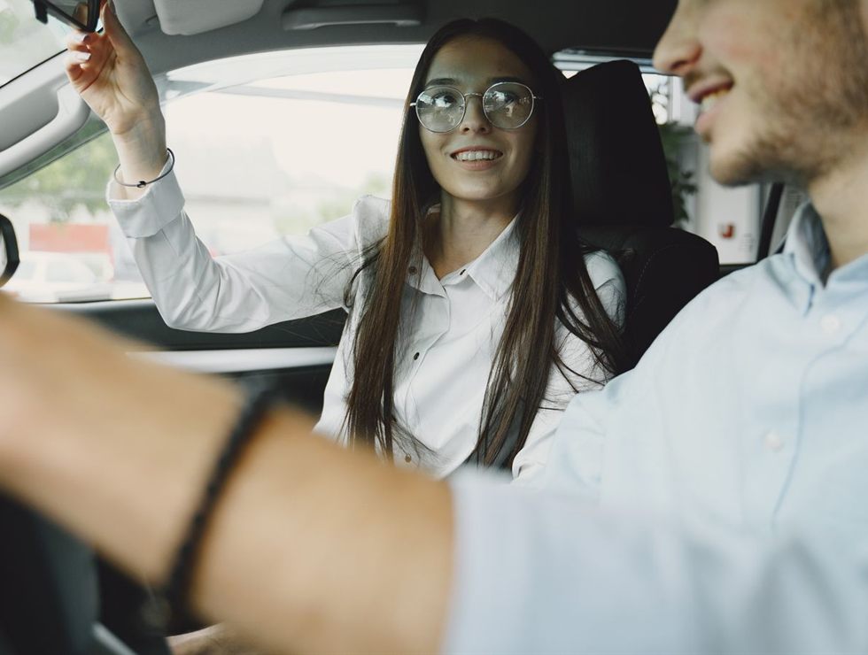 Instrutora ajustando o retrovisor antes de o aluno sair com o carro